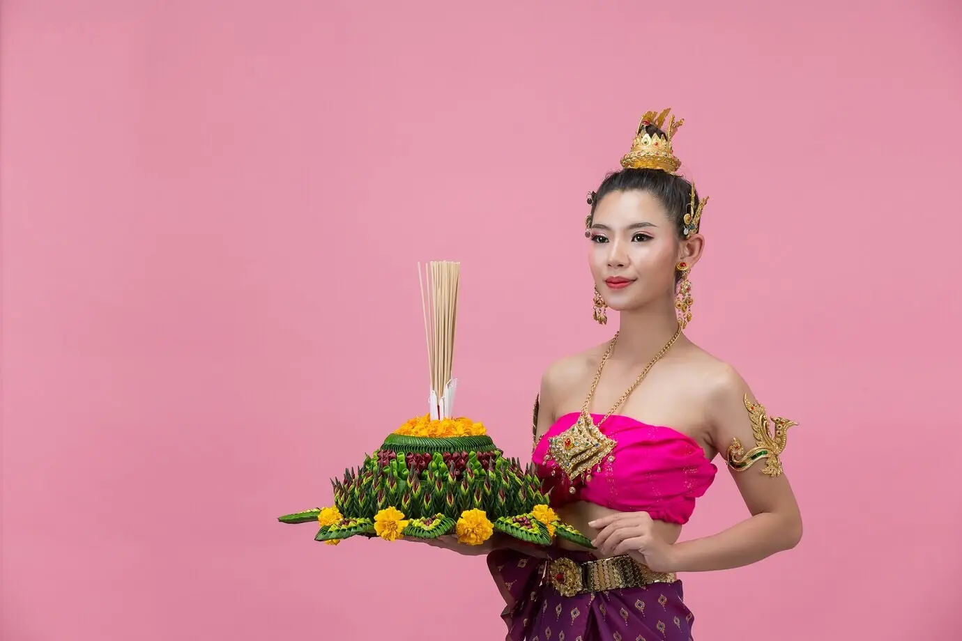 Loy-Krathong-Festival. Eine Frau in traditioneller thailändischer Kleidung hält einen dekorierten schwimmfähigen Gegenstand.